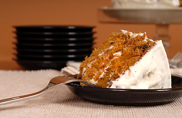 Image showing Piece of carrot cake with plates in background