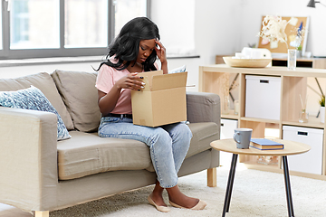 Image showing sad african american woman with parcel box at home