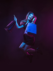 Image showing Portrait of young woman in neon light on dark backgound. The human emotions, black friday, cyber monday, purchases, sales, finance concept.