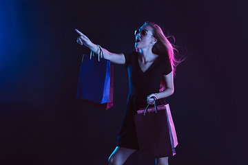 Image showing Portrait of young woman in neon light on dark backgound. The human emotions, black friday, cyber monday, purchases, sales, finance concept.