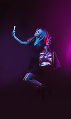 Image showing Portrait of young woman in neon light on dark backgound. The human emotions, black friday, cyber monday, purchases, sales, finance concept.