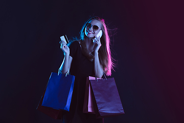 Image showing Portrait of young woman in neon light on dark backgound. The human emotions, black friday, cyber monday, purchases, sales, finance concept.