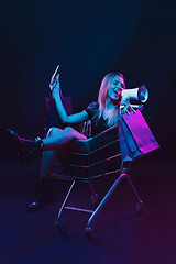 Image showing Portrait of young woman in neon light on dark backgound. The human emotions, black friday, cyber monday, purchases, sales, finance concept.