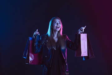 Image showing Portrait of young woman in neon light on dark backgound. The human emotions, black friday, cyber monday, purchases, sales, finance concept.