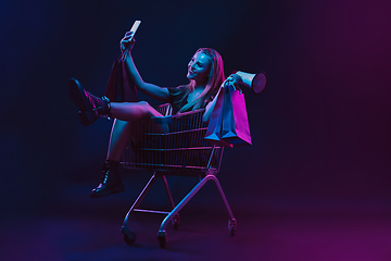 Image showing Portrait of young woman in neon light on dark backgound. The human emotions, black friday, cyber monday, purchases, sales, finance concept.