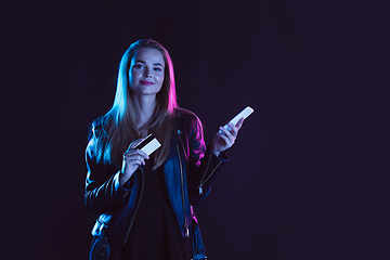 Image showing Portrait of young woman in neon light on dark backgound. The human emotions, black friday, cyber monday, purchases, sales, finance concept.