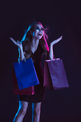 Image showing Portrait of young woman in neon light on dark backgound. The human emotions, black friday, cyber monday, purchases, sales, finance concept.