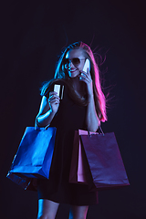 Image showing Portrait of young woman in neon light on dark backgound. The human emotions, black friday, cyber monday, purchases, sales, finance concept.