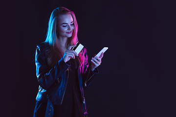 Image showing Portrait of young woman in neon light on dark backgound. The human emotions, black friday, cyber monday, purchases, sales, finance concept.