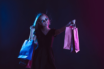 Image showing Portrait of young woman in neon light on dark backgound. The human emotions, black friday, cyber monday, purchases, sales, finance concept.