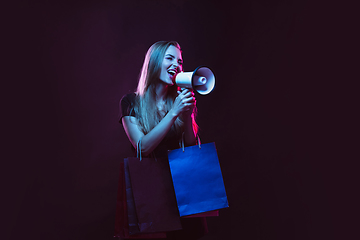 Image showing Portrait of young woman in neon light on dark backgound. The human emotions, black friday, cyber monday, purchases, sales, finance concept.