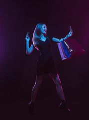 Image showing Portrait of young woman in neon light on dark backgound. The human emotions, black friday, cyber monday, purchases, sales, finance concept.