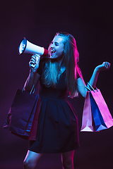Image showing Portrait of young woman in neon light on dark backgound. The human emotions, black friday, cyber monday, purchases, sales, finance concept.