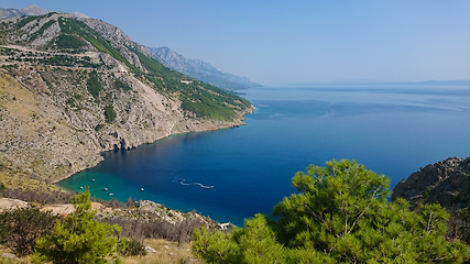 Image showing Rocky beach, bue transparent sea with boats