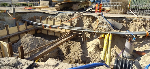 Image showing The process of laying of engineering and heating systems. Many multicolored plastic pipes are in a trench of sand in perspective