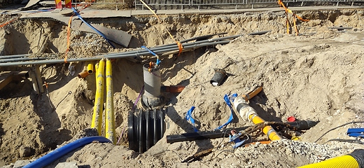 Image showing The process of laying of engineering and heating systems. Many multicolored plastic pipes are in a trench of sand in perspective