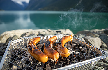 Image showing Grilling sausages on disposable barbecue grid.