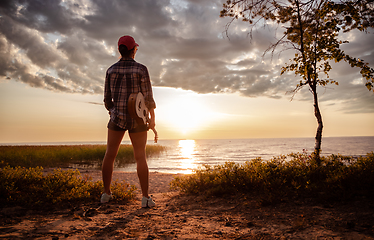 Image showing Woman at sunset holding a ukulele