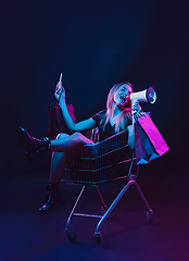 Image showing Portrait of young woman in neon light on dark backgound. The human emotions, black friday, cyber monday, purchases, sales, finance concept.