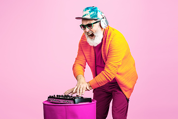 Image showing Senior hipster man wearing eyeglasses posing on pink background. Tech and joyful elderly lifestyle concept