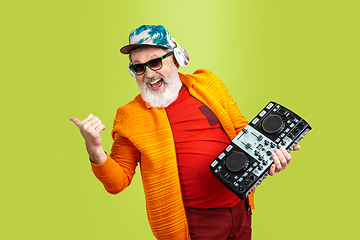 Image showing Senior hipster man wearing eyeglasses posing on green background. Tech and joyful elderly lifestyle concept