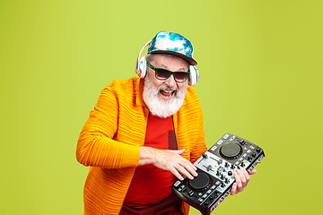 Image showing Senior hipster man wearing eyeglasses posing on green background. Tech and joyful elderly lifestyle concept