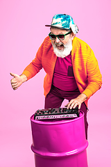 Image showing Senior hipster man wearing eyeglasses posing on pink background. Tech and joyful elderly lifestyle concept