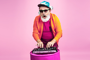 Image showing Senior hipster man wearing eyeglasses posing on pink background. Tech and joyful elderly lifestyle concept