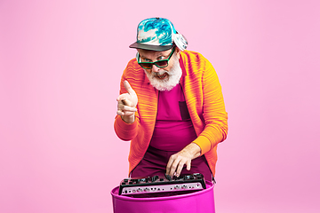 Image showing Senior hipster man wearing eyeglasses posing on pink background. Tech and joyful elderly lifestyle concept