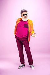 Image showing Senior hipster man wearing eyeglasses posing on pink background. Tech and joyful elderly lifestyle concept