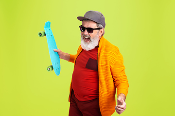 Image showing Senior hipster man wearing eyeglasses posing on green background. Tech and joyful elderly lifestyle concept