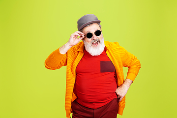 Image showing Senior hipster man wearing eyeglasses posing on green background. Tech and joyful elderly lifestyle concept