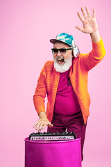 Image showing Senior hipster man wearing eyeglasses posing on pink background. Tech and joyful elderly lifestyle concept