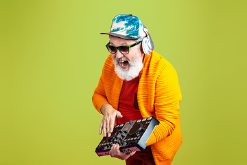 Image showing Senior hipster man wearing eyeglasses posing on green background. Tech and joyful elderly lifestyle concept