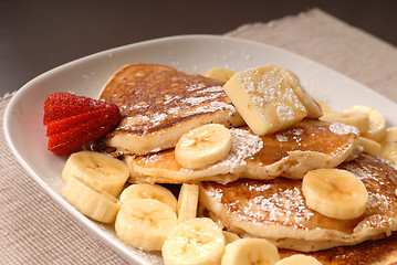 Image showing Banana pancakes with maple syrup and a strawberrry