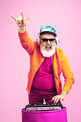 Image showing Senior hipster man wearing eyeglasses posing on pink background. Tech and joyful elderly lifestyle concept