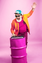 Image showing Senior hipster man wearing eyeglasses posing on pink background. Tech and joyful elderly lifestyle concept