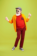 Image showing Senior hipster man wearing eyeglasses posing on green background. Tech and joyful elderly lifestyle concept