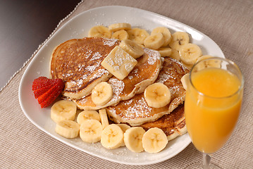 Image showing Banana pancakes with maple syrup, a strawberrry and orange juice