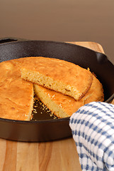 Image showing Cornbread in a cast iron skillet with piece cut out