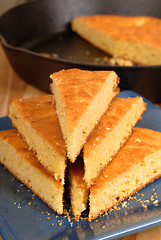 Image showing Stack of cornbread on blue plate with black skillet in backgroun