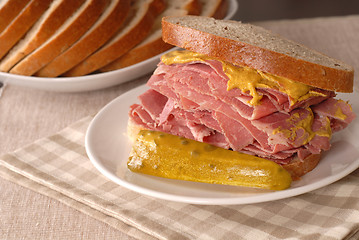 Image showing Corned beef sandwich with mustard and pickle on rye