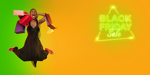 Image showing Portrait of young woman in neon light on gradient backgound. The human emotions, black friday, cyber monday, purchases, sales, finance concept. Neoned lettering.