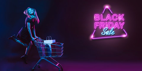 Image showing Portrait of young woman in neon light on dark backgound. The human emotions, black friday, cyber monday, purchases, sales, finance concept. Neoned lettering.