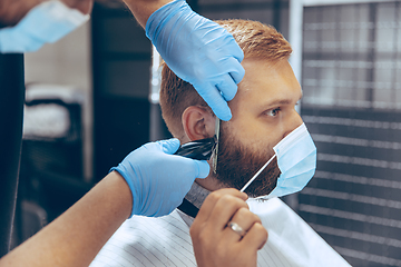 Image showing Man getting hair cut at the barbershop wearing mask during coronavirus pandemic