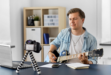 Image showing man or blogger with camera playing guitar at home