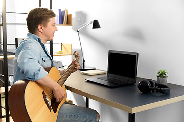 Image showing young man with laptop and guitar at home