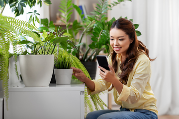 Image showing asian woman with smartphone and flowers at home