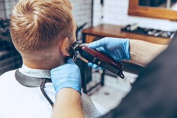 Image showing Man getting hair cut at the barbershop wearing mask during coronavirus pandemic