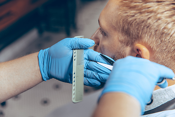 Image showing Man getting hair cut at the barbershop wearing mask during coronavirus pandemic